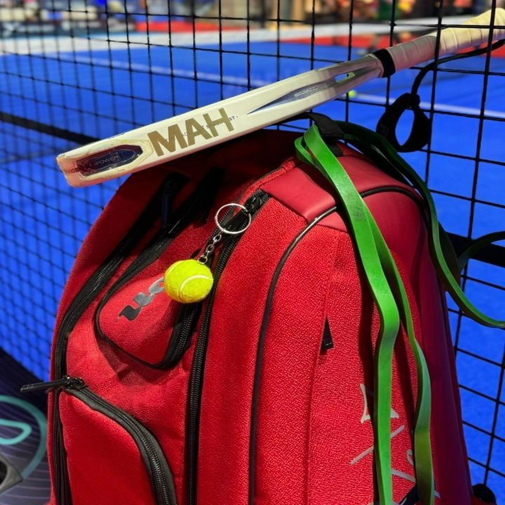 Red sports bag with a tennis racket and ball on a blue court background